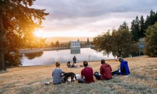 people enjoy a picnic at sunset looking out over a reservoir