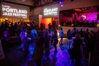 A full bar of people talking, dancing and ordering drinks.