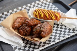an order of tempting glazed chicken wings and a corndog crisscrossed with ketchup and mustard