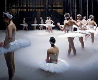 more than a dozen ballerinas in white tutus on a stage covered in a white mist