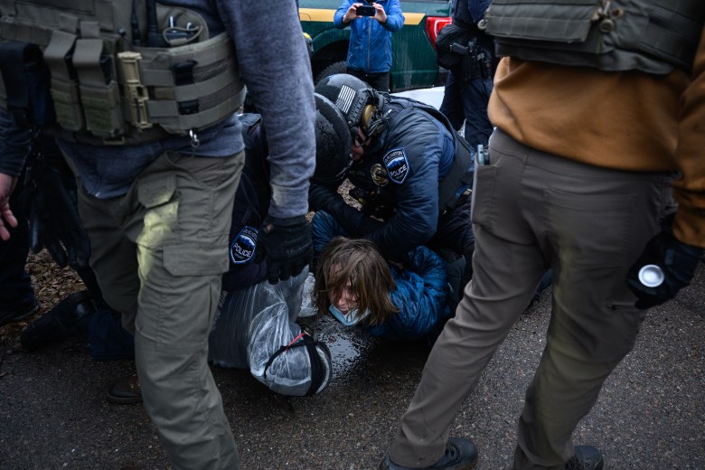 A protester is pinned to the ground by two Burlington police officers