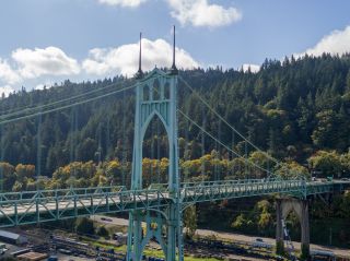 view of historic bridge with tree filled mountains and blue sky in the background