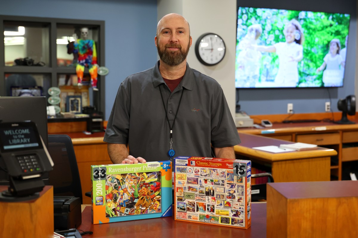 Person holding two puzzle boxes.