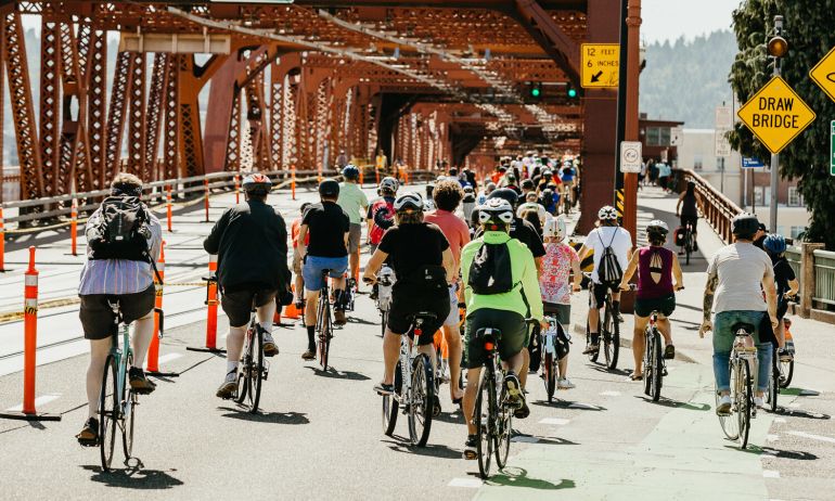 a crowd of people biking across a bridge