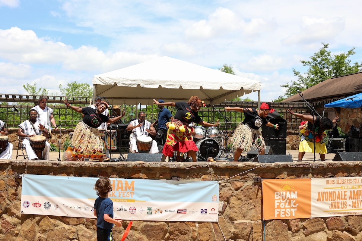 A child watches as dancers perform to drumming at the Birmingham Folk Festival in Avondale Park, Birmingham, Alabama