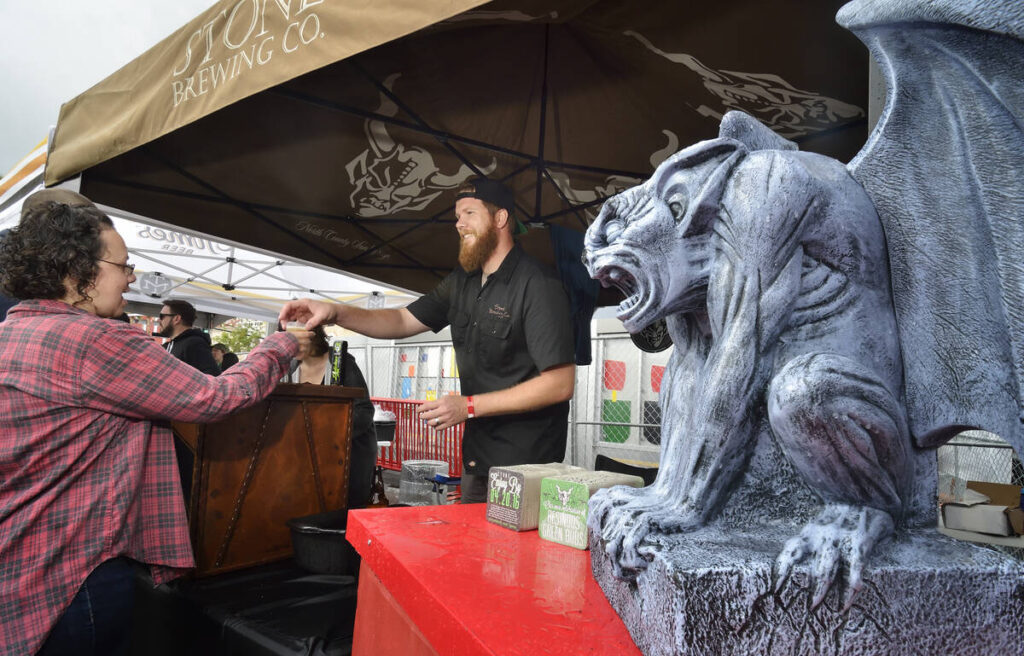 Adam Quinn, center, hands a beer sample to a festival goer at the Stone Brewing company tent du ...
