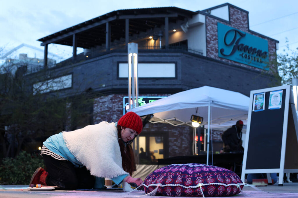 Robin Slonina, a board member for the 18b Arts District Association, draws a flower with chalk ...