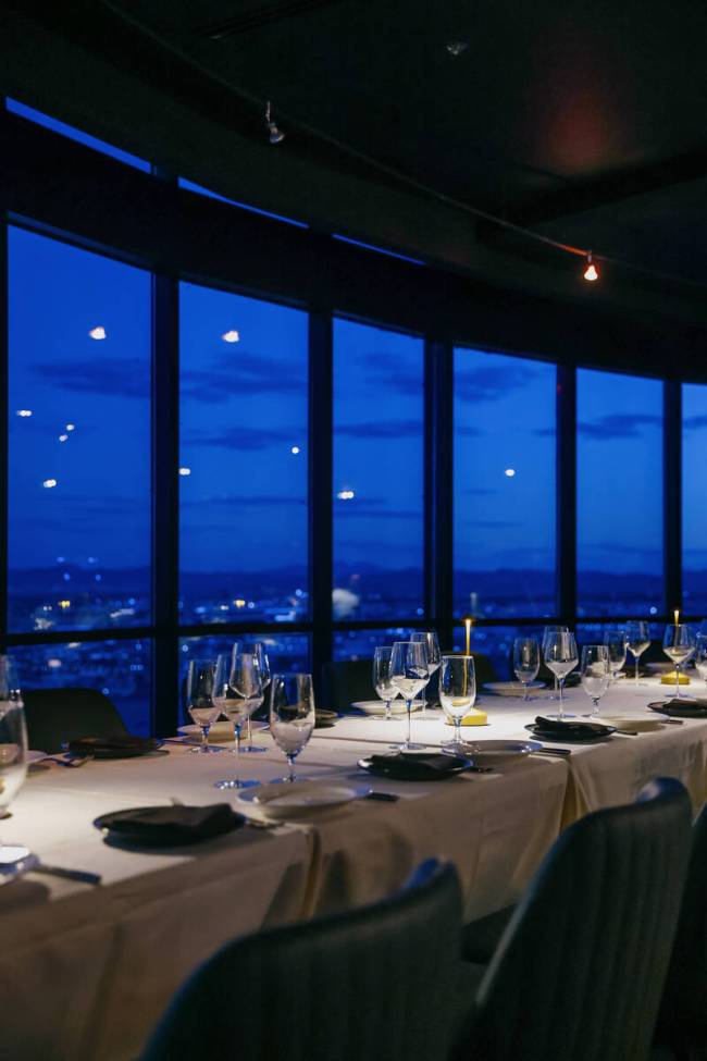 Tables are set against the backdrop of an evening skyline view at High Steaks at Rio Hotel & ...
