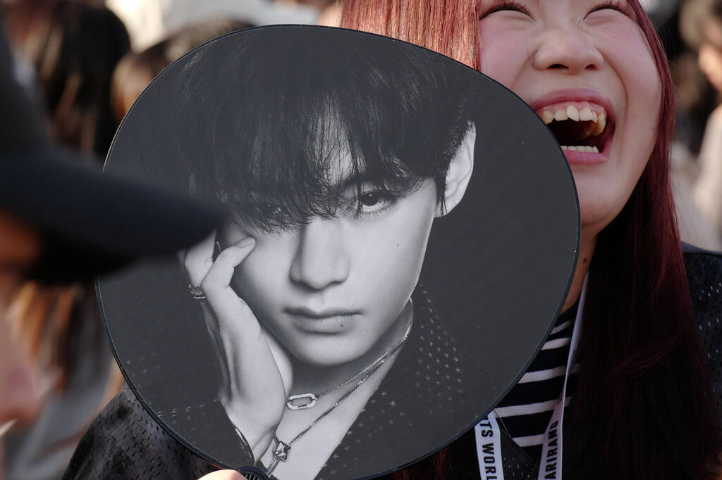 A K-pop fan smiles prior to the BTS World Tour concert outside Tokyo Dome Friday, April 17, 202 ...
