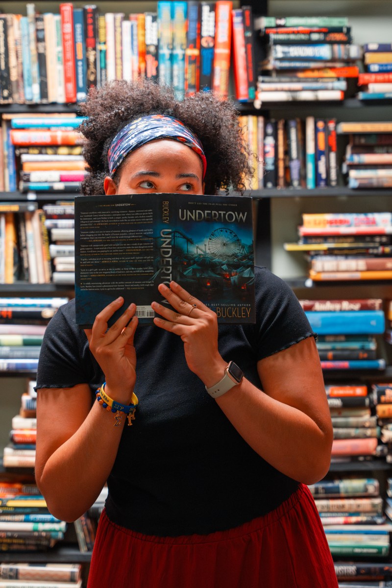 39 July events to experience—festivals, firework shows + more 3 Person holding up the book Undertow by Buckley at Jim Reed Bookstore, surrounded by shelves of books