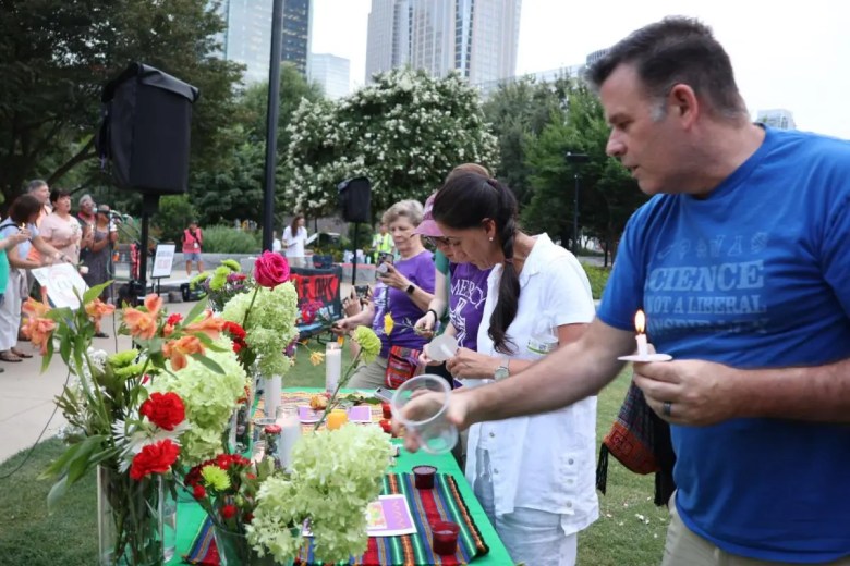 Attendees at the vigil place flowers on photographs of Mexican worker Lorenzo Salgado Araujo and young Colombian Johan Sebastián Guerrero, who died a week apart, on July 7 and 13, after being shot by ICE agents in Texas and Maine. Photo Credit: Patricia Ortiz