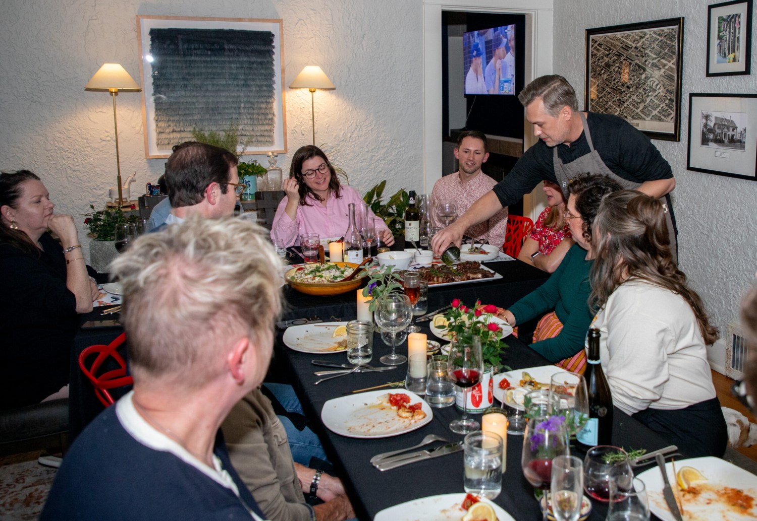 How to get tickets now for the Picasso Pets gala—give back + win a trip to Italy, August 22 5 A chef in an apron serves food to guests seated around a candlelit dinner table with wine and shared dishes