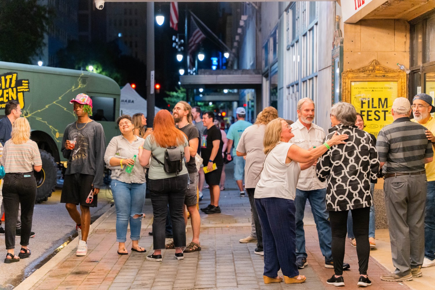 Everything you need to know about the 28th Sidewalk Film Festival in Birmingham (August 24-30, 2026) 4 Crowd of attendees socializing on a city sidewalk at night during the Sidewalk Film Festival