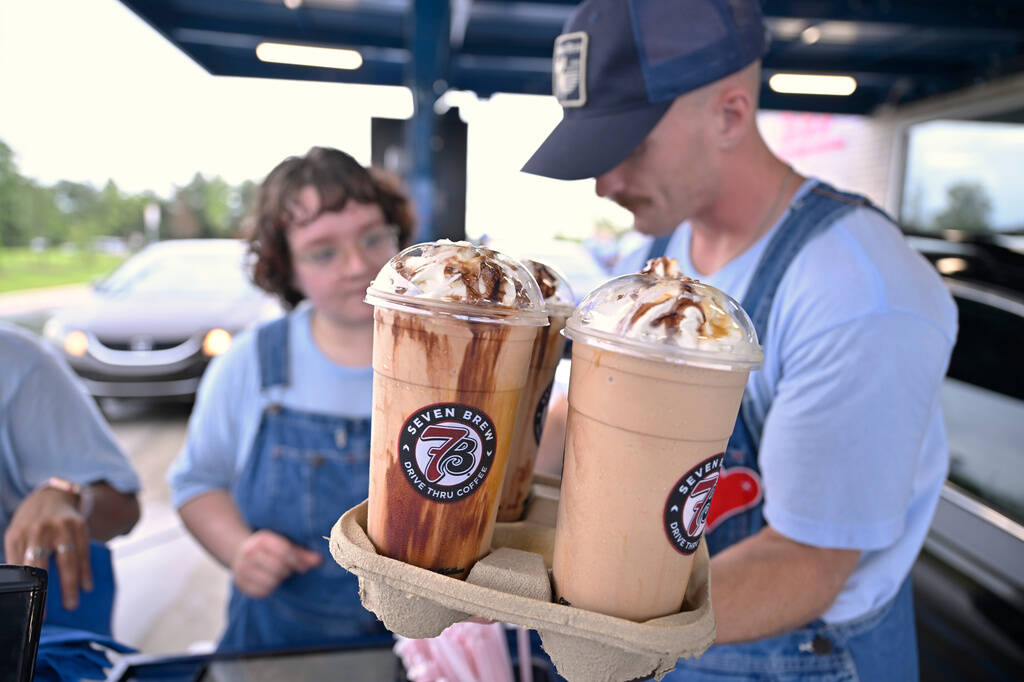 Brew Crew team members serve drinks to customers during 7 Brew's 777 stands celebration on Mond ...
