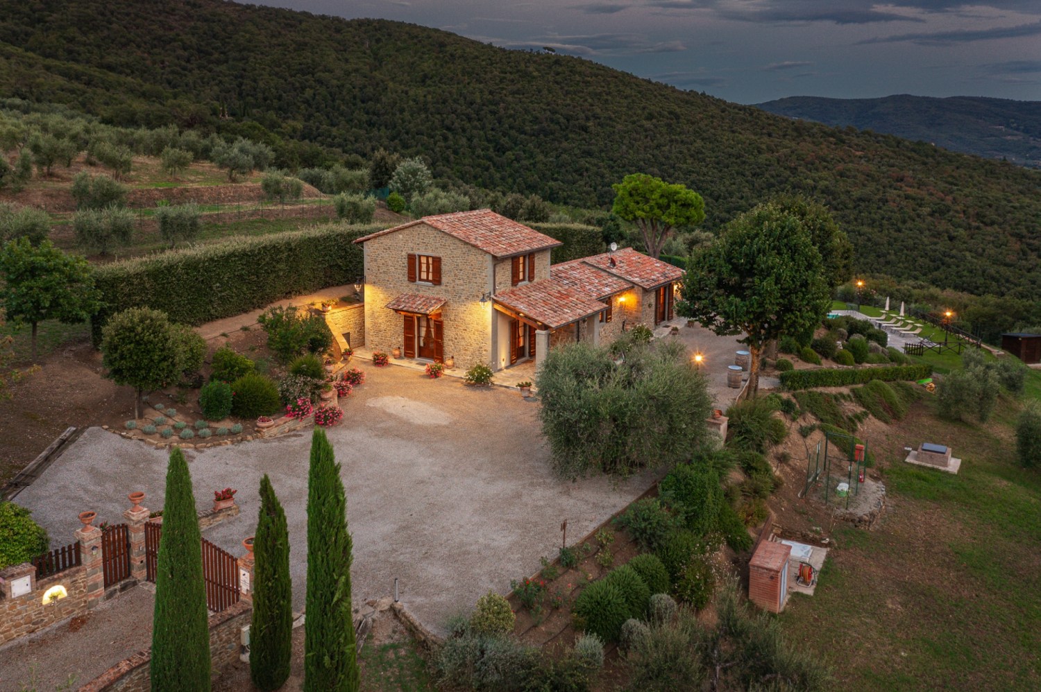 How to get tickets now for the Picasso Pets gala—give back + win a trip to Italy, August 22 6 Aerial dusk view of a stone Tuscan farmhouse with terracotta roof, lit courtyard, cypress trees, gardens, and hillside surroundings
