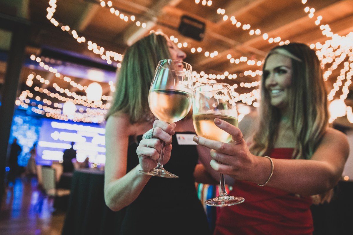two women cheers wine glasses at a prior Enchanted Evening event