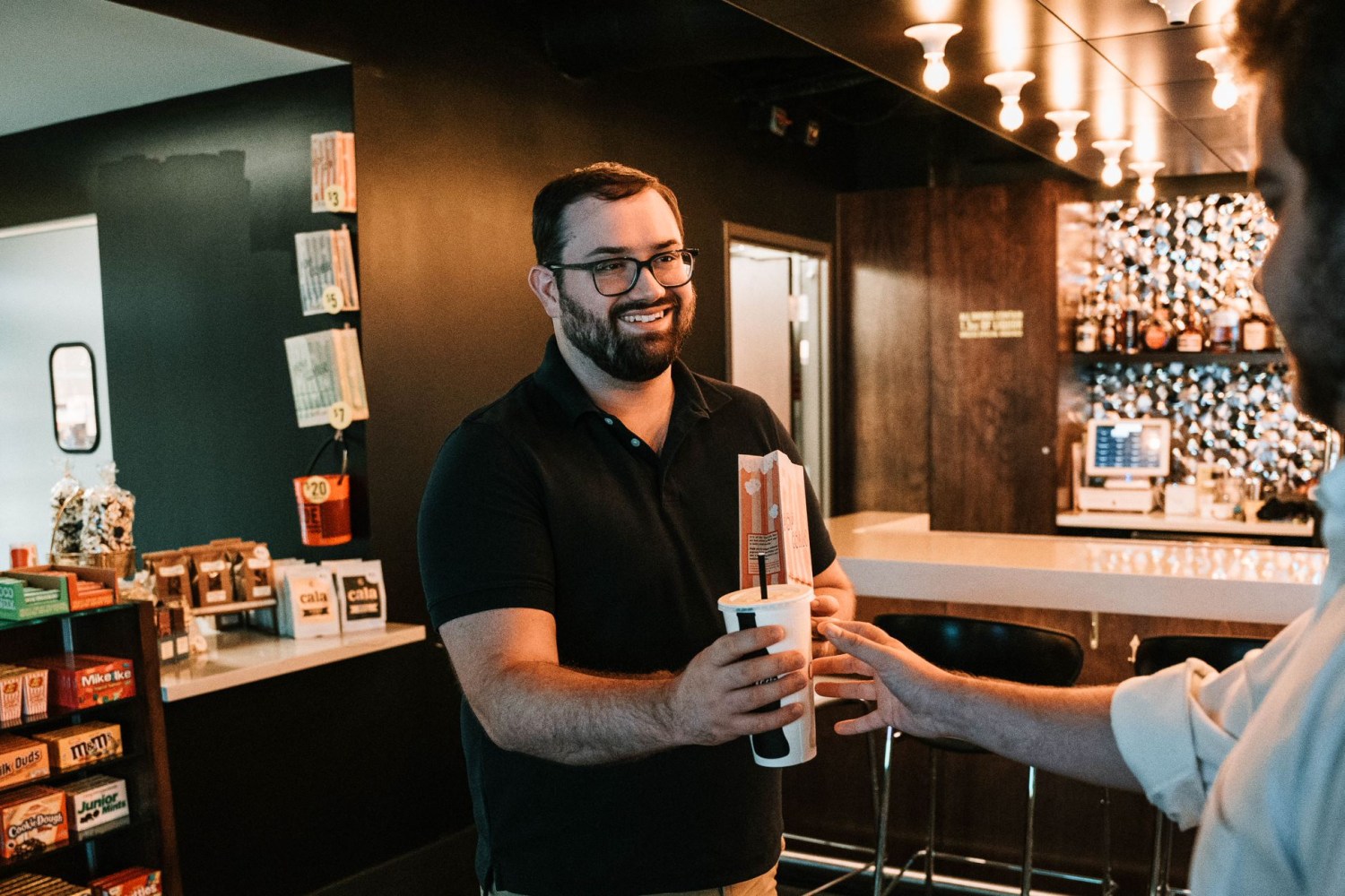 a man holding popcorn and a drink at a movie theater