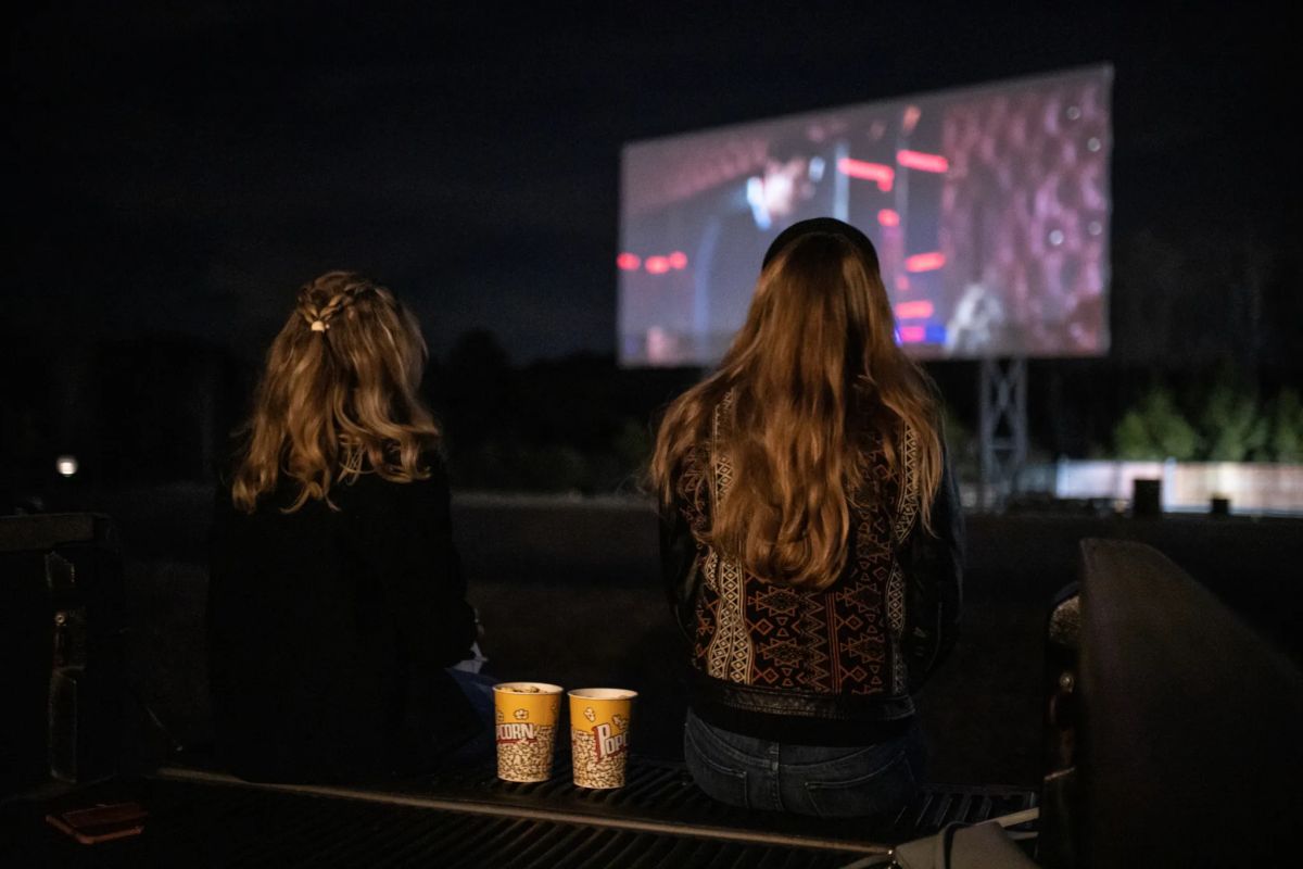Outdoor Movies in Birmingham: 5 spots to watch this fall 4 Two people sit in a truck bed with popcorn, watching a movie on the big screen at Grand River Drive-In