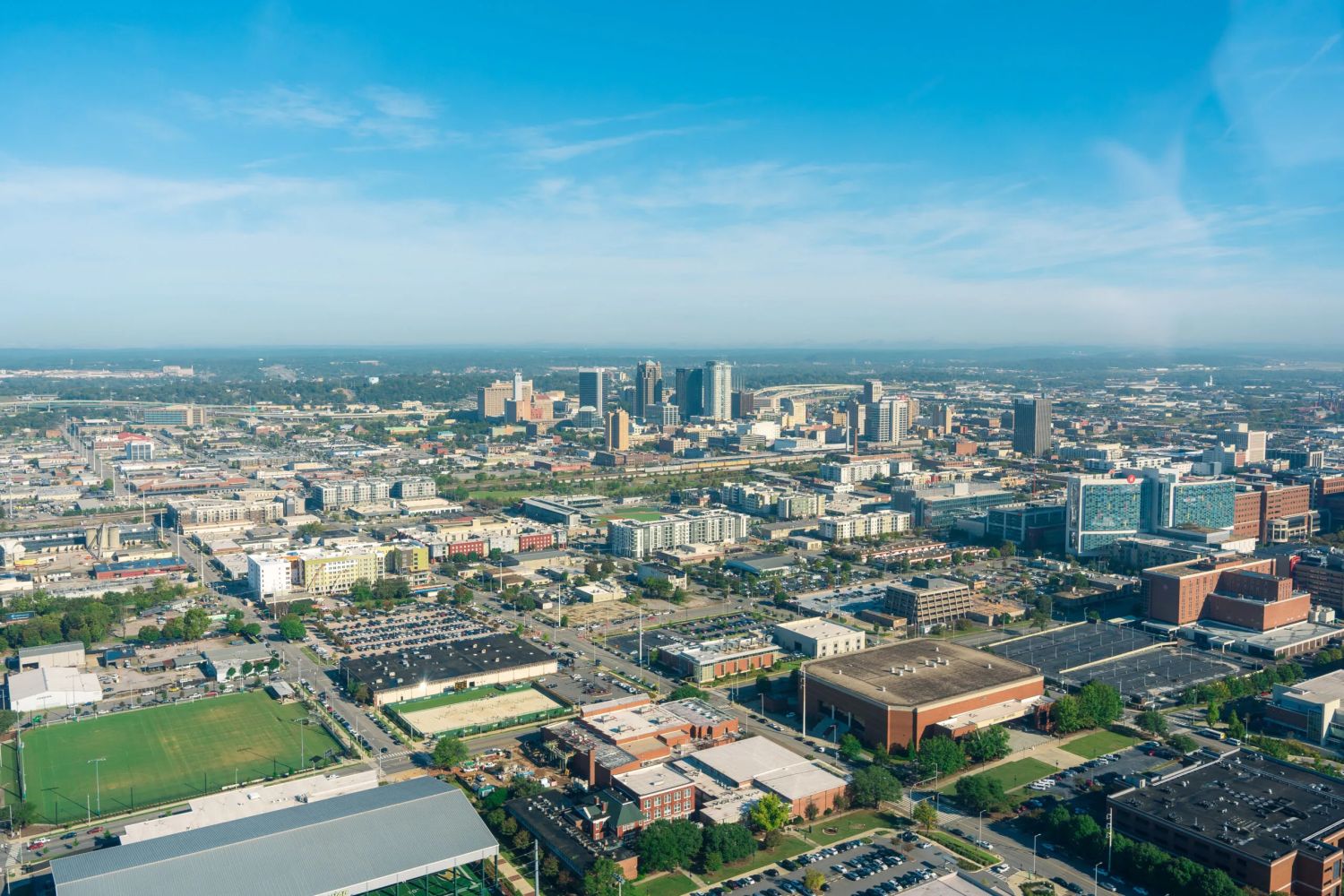 Birmingham recieves Medal of Honor Society Convention flag as 2027 Host City 4 Aerial view of a city skyline with downtown skyscrapers surrounded by low-rise buildings, parking lots, and sports fields