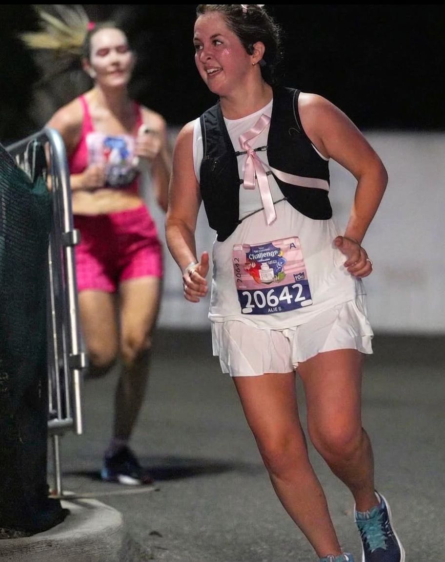 Runner wearing bib 20642 for the 2015 Tinker Bell Challenge, running a nighttime race in a pink dress with black vest
